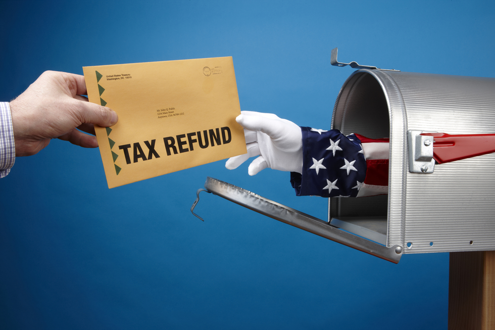 Arm of Uncle Sam delivering a tax refund out of a mailbox