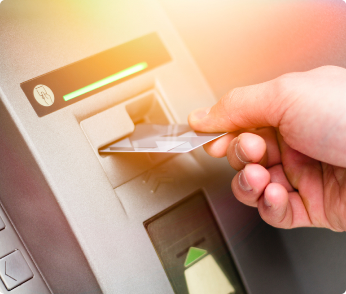 Man's hands inserting a debit card in an ATM slot