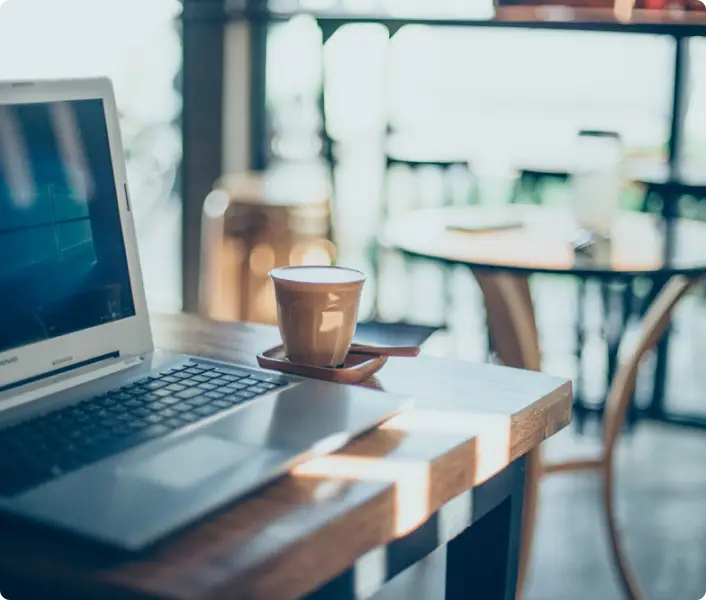 Coffee cup next to laptop on a tabletop