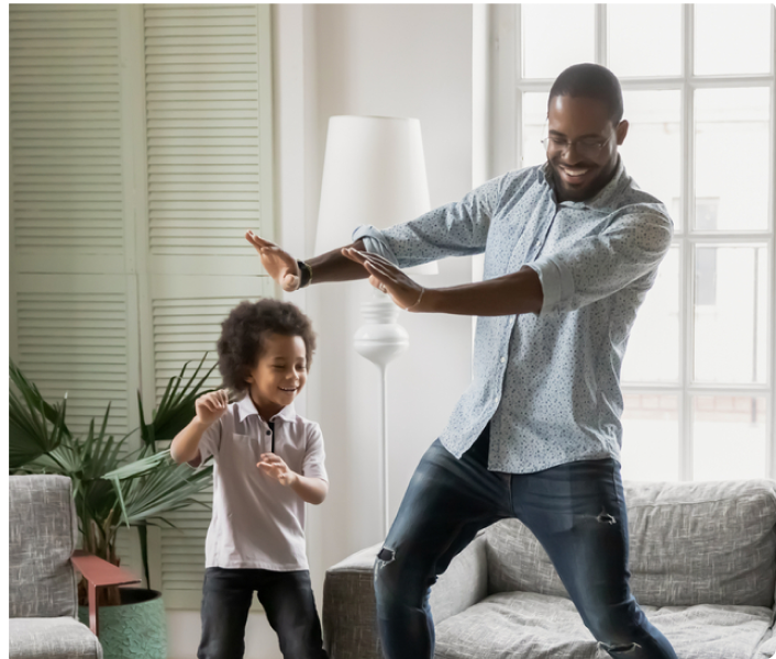 Dad and son dancing in a living room