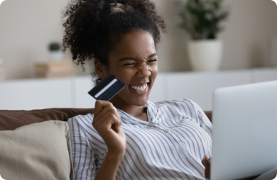 Young adult woman holding a debit card and looking at a laptop screen