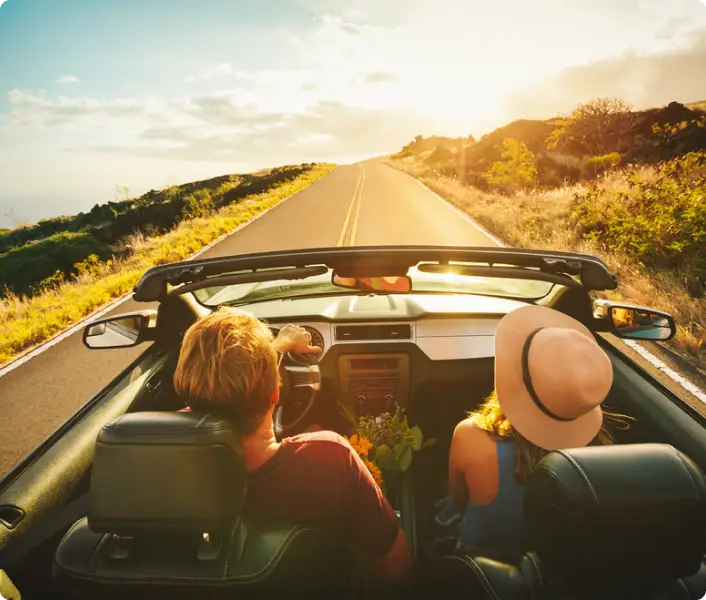 Young couple driving on a highway towards the the sunset